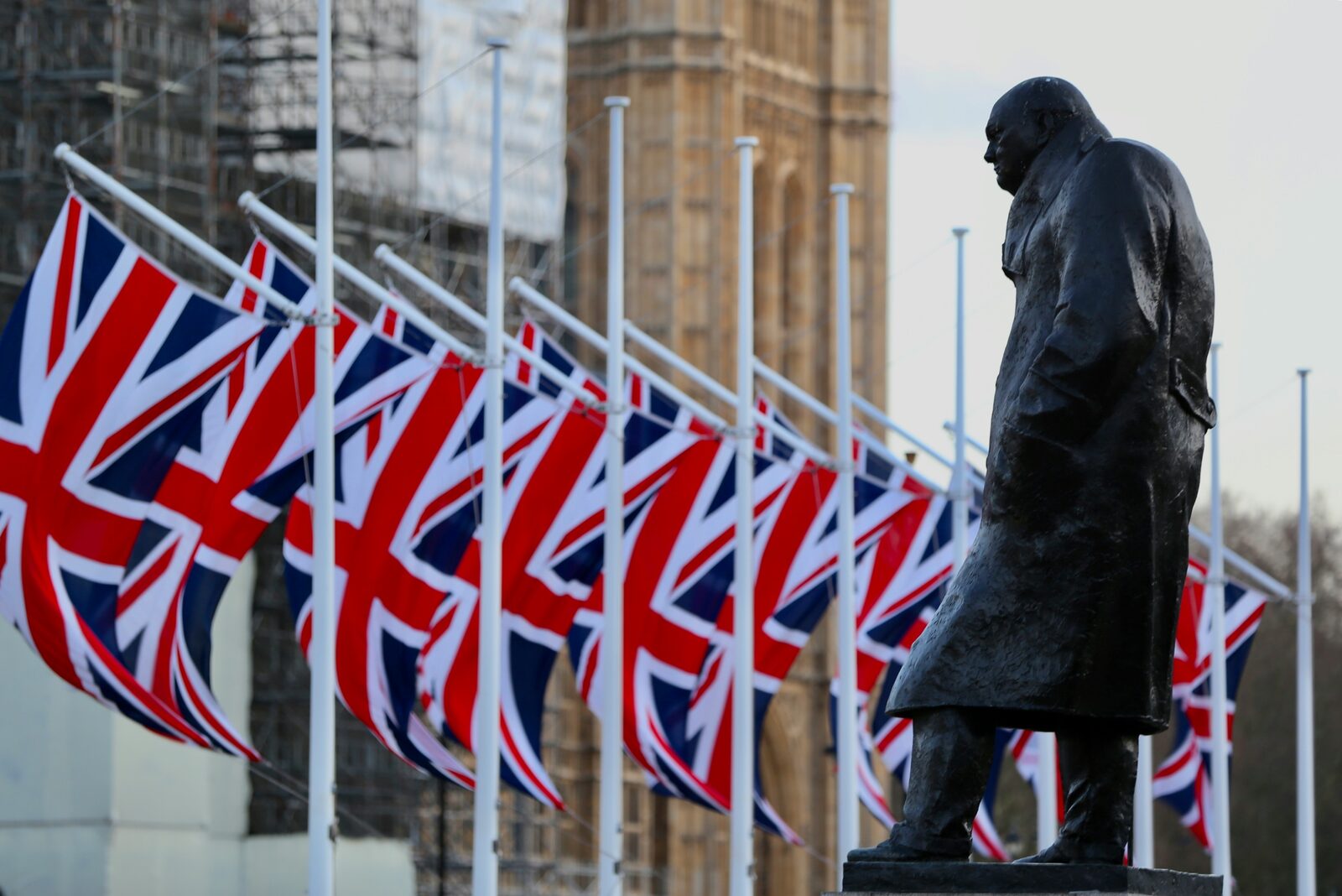 Churchill statue with Union Jack flags in front of the Houses of Parliament, London